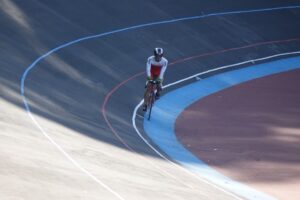 Baanrenner op een vaste fiets in een bocht van de wielerbaan