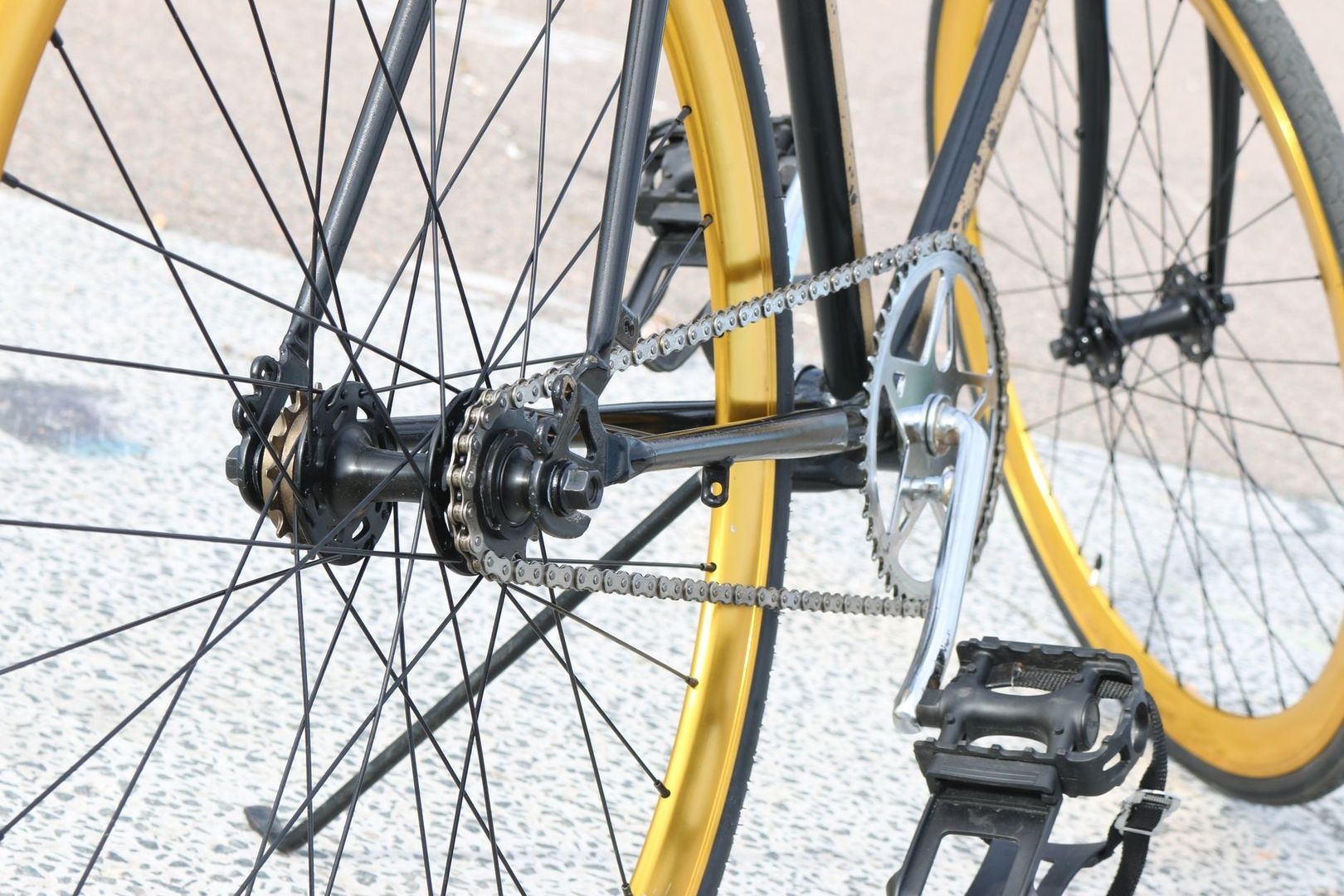 Close-up van de ketting en vaste aandrijving van een gele fiets